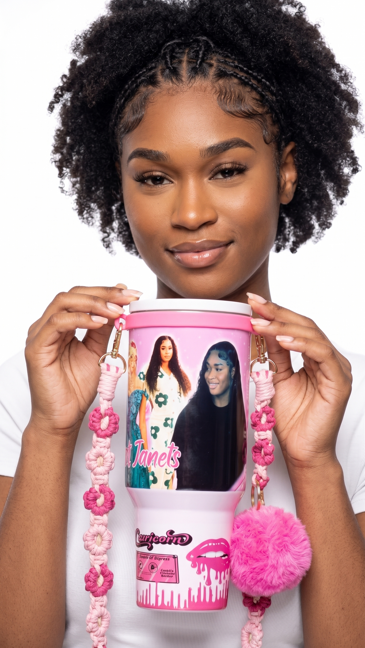 A woman holding a pink custom-printed tumbler with a matching pink beaded strap and pom-pom charm against a white background.